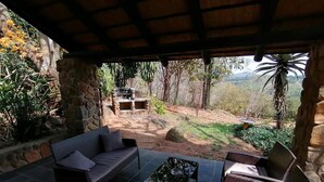 Un patio al aire libre con mobiliario de mimbre y un pilar de piedra.