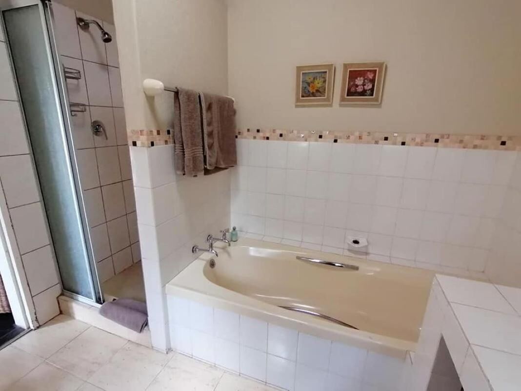 A bathroom with a bathtub, a shower, and a toilet. There are two framed pictures on the wall.