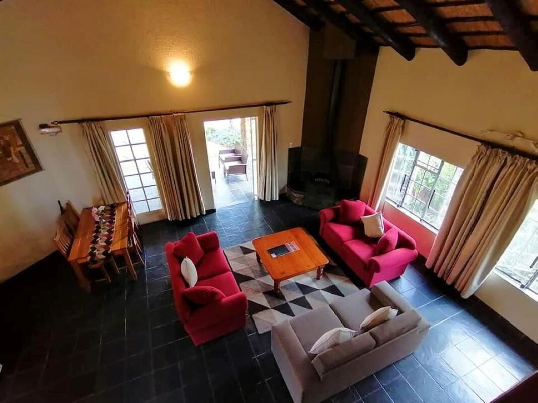 Un salón espacioso con chimenea, un comedor con mesa y sillas de madera, y un amplio ventanal con cortinas.