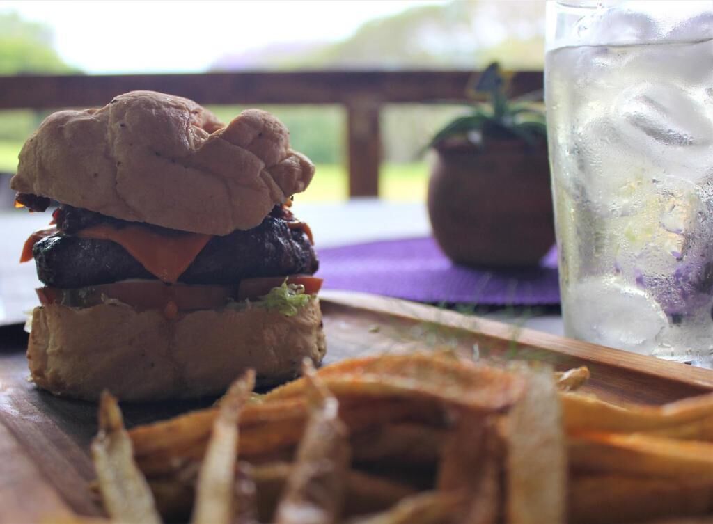 A burger with fries and a drink on a wooden table.