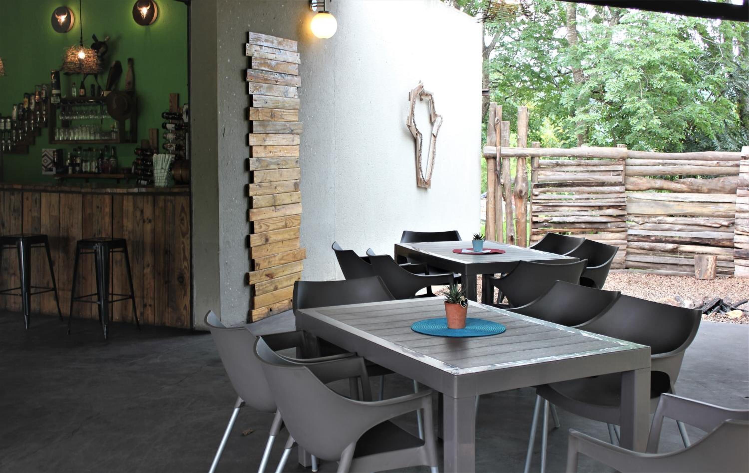 Un patio al aire libre con barra, asientos y una pared de madera rústica.
