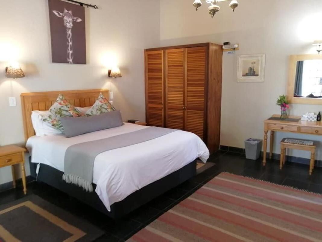 Ein Schlafzimmer mit Bett, Holzschrank, Nachttischlampen, Schreibtisch und Spiegel.