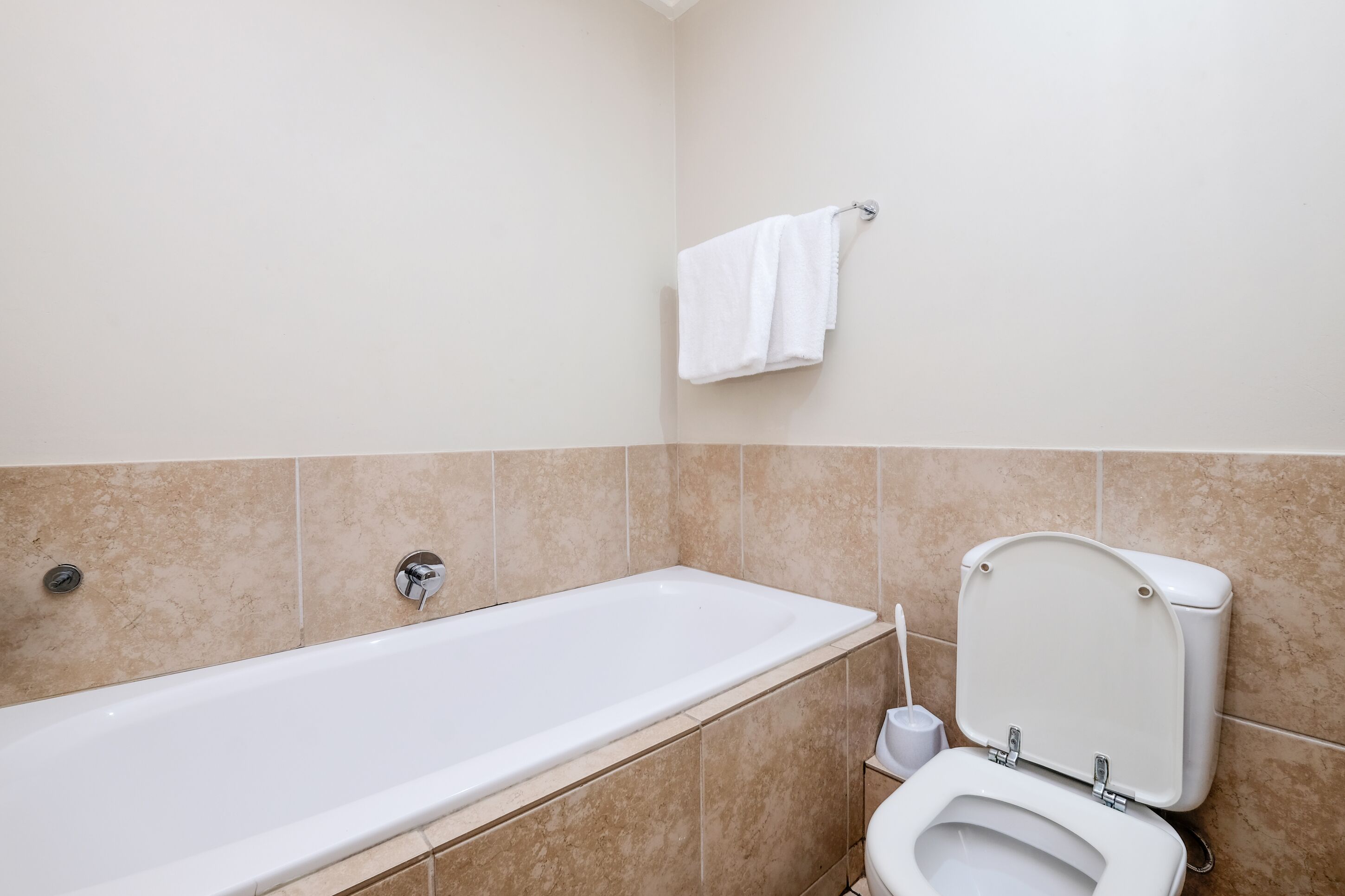 Un baño con bañera, inodoro y barra para toallas.
