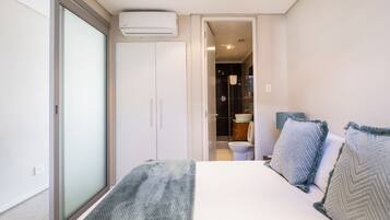 A bedroom with a bed, a wardrobe, and a bathroom visible through an open door.