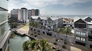A modern hotel with multiple floors, a canal in front, and a view of the beach and ocean. - Point Waterfront Apartments (Durban)