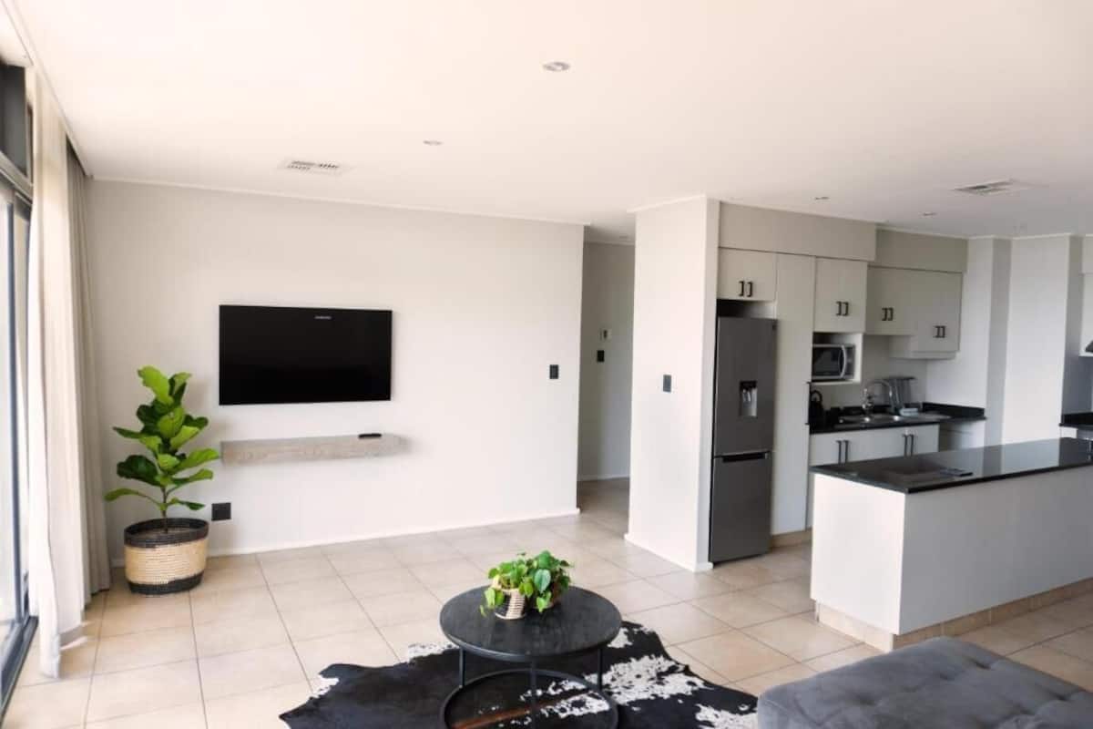 A modern kitchen with a central island, built-in appliances, and a flat-screen TV mounted on the wall.