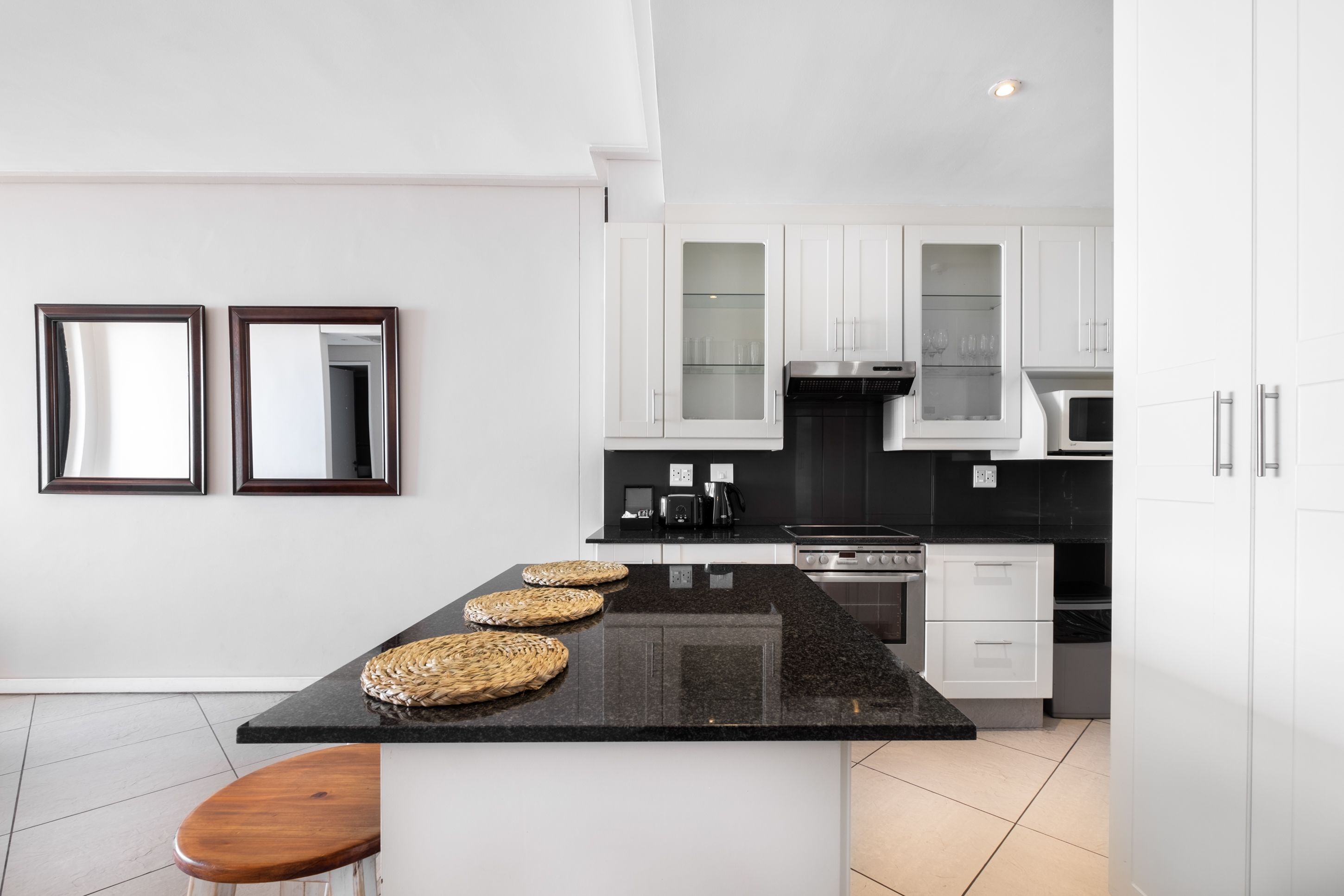 A modern kitchen with white cabinets, a black granite countertop, and a central island with woven baskets.
