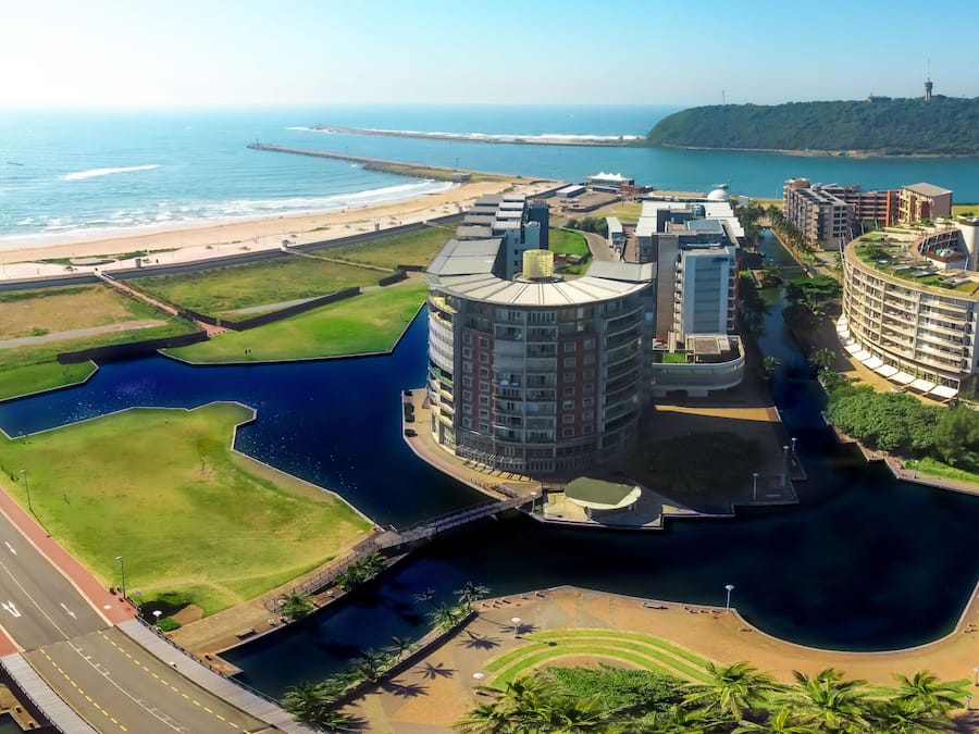 A coastal urban area with modern buildings, a marina, and a beach.