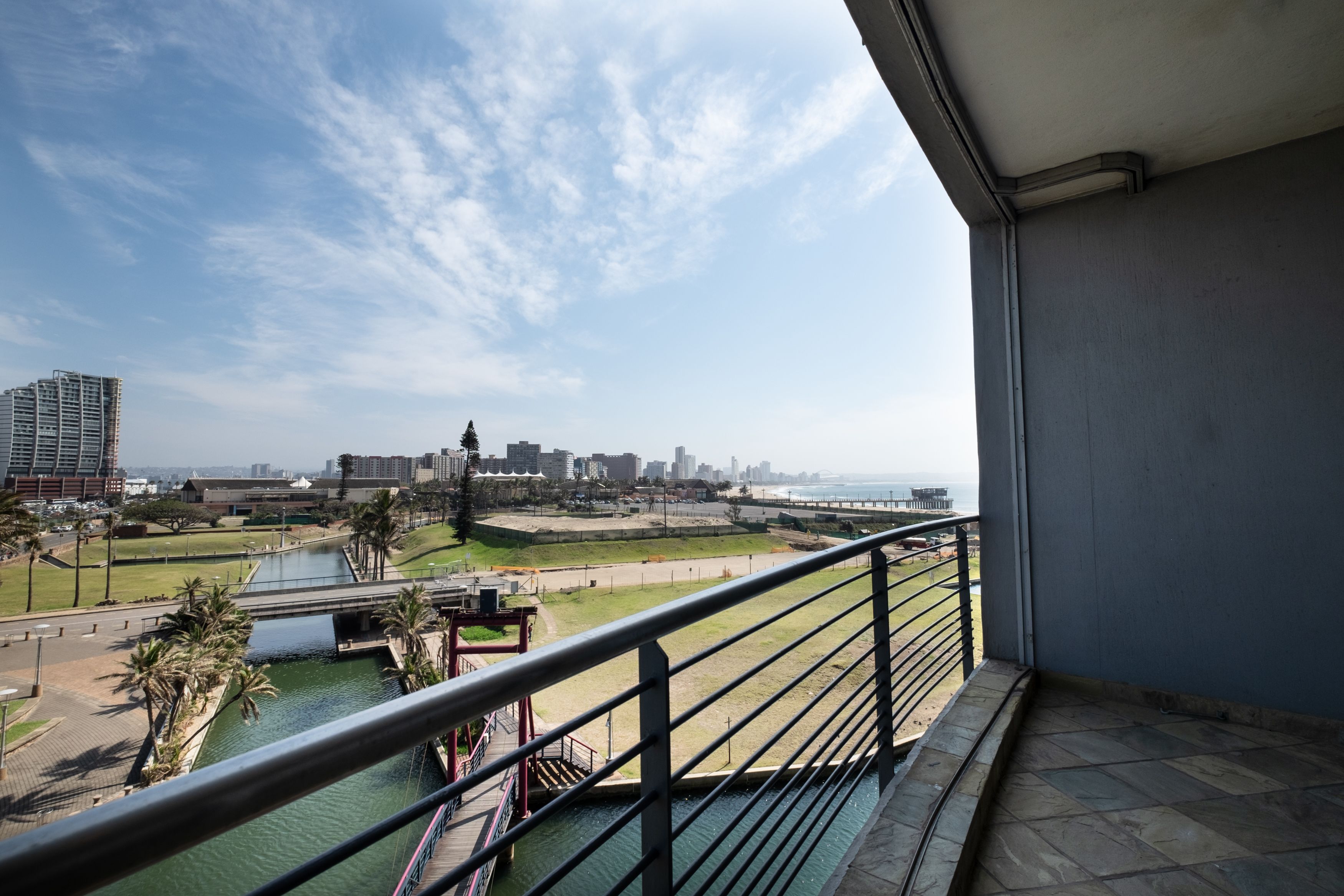 Un balcón con vista a un río, un puente y un paisaje urbano a lo lejos.