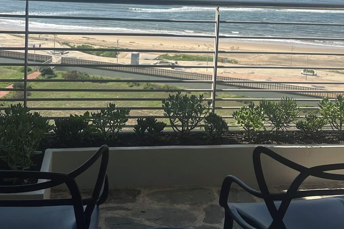 A balcony with a view of the beach and ocean.