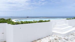 A white infinity pool with a stone floor, surrounded by white walls and steps leading to a deck. - Point Waterfront Apartments (Durban)