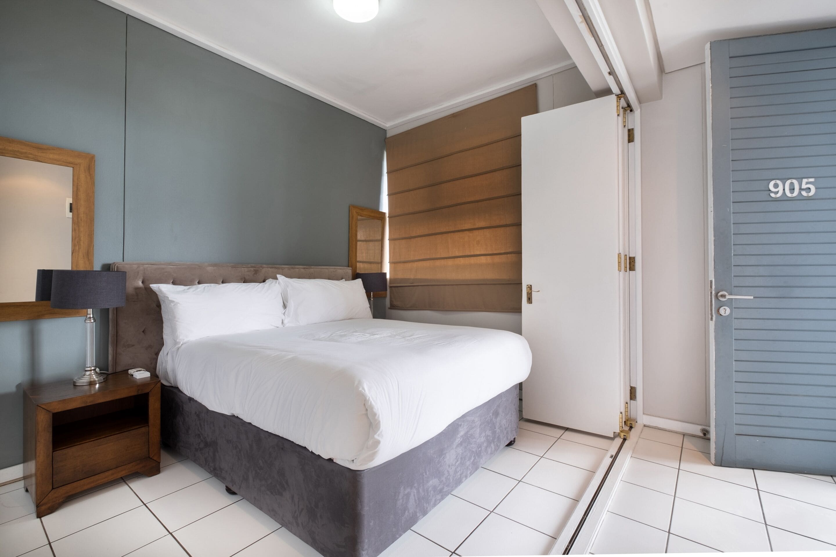 Un dormitorio con cama, mesita de noche y una puerta con el número 905.
