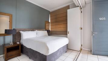 Un dormitorio con cama, mesita de noche y una puerta con el número 905.