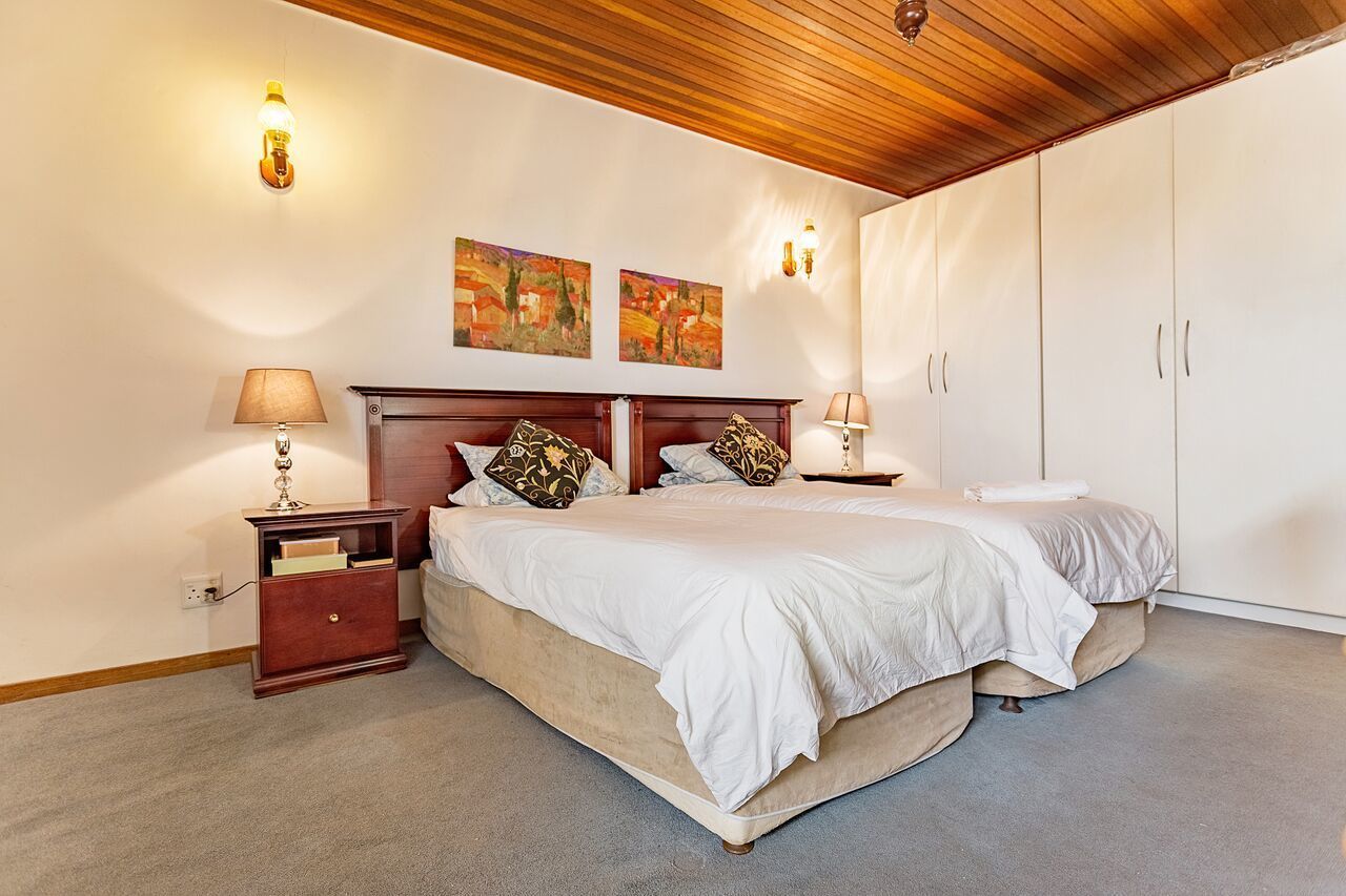 Un dormitorio con una cama grande, dos mesitas de noche, techo de madera y una obra de arte en la pared.