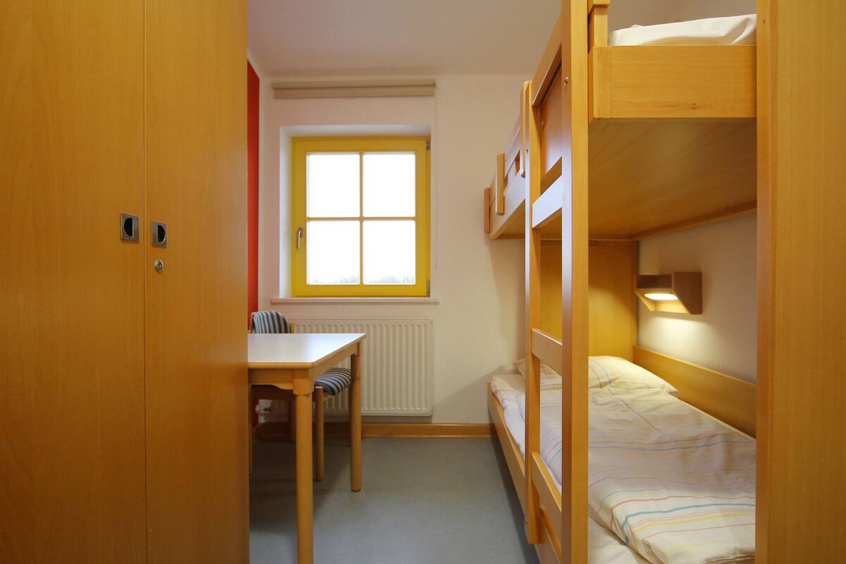 A room with a bunk bed, a desk, and a chair.
