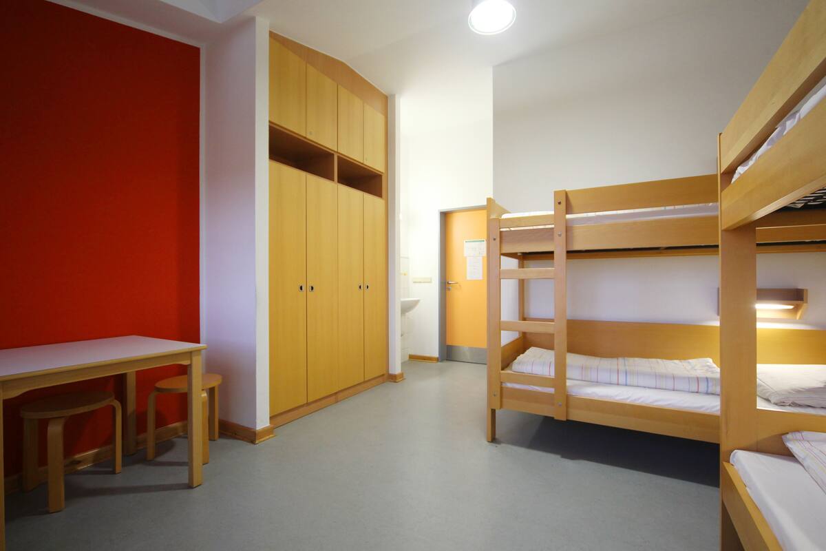 A room with bunk beds, a desk, and a wardrobe.