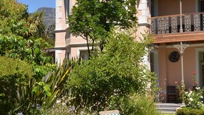 Ein zweistöckiges Haus mit Balkon, umgeben von üppigem Grün und einem gepflegten Rasen.