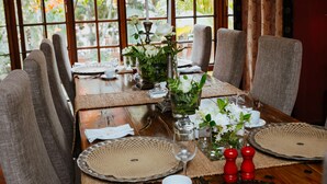 Ein Esstisch, gedeckt mit Platzsets, Kerzen und einer Blumenarragemment.