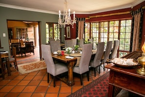 A dining area with a wooden table, grey upholstered chairs, and a chandelier.