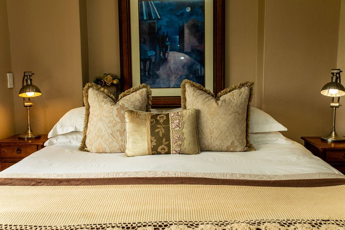A neatly made bed with patterned pillows and a framed artwork above it.