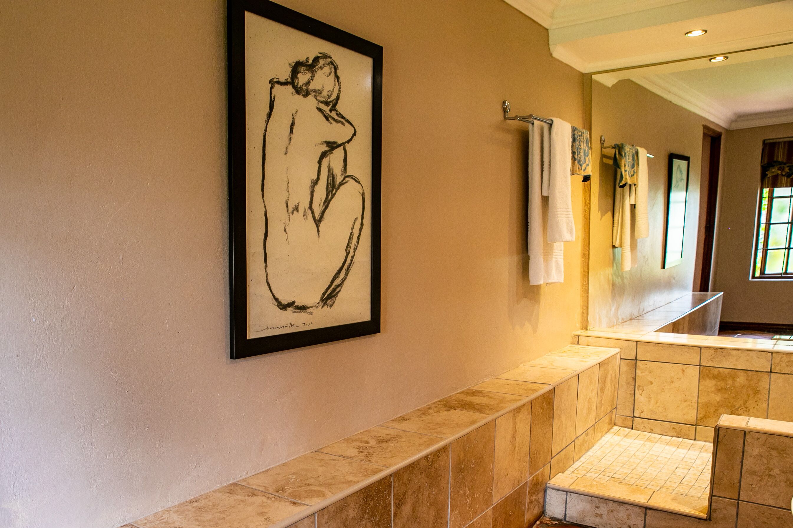 A hallway with a framed abstract painting, a tiled bench, and a row of towels on a rack.