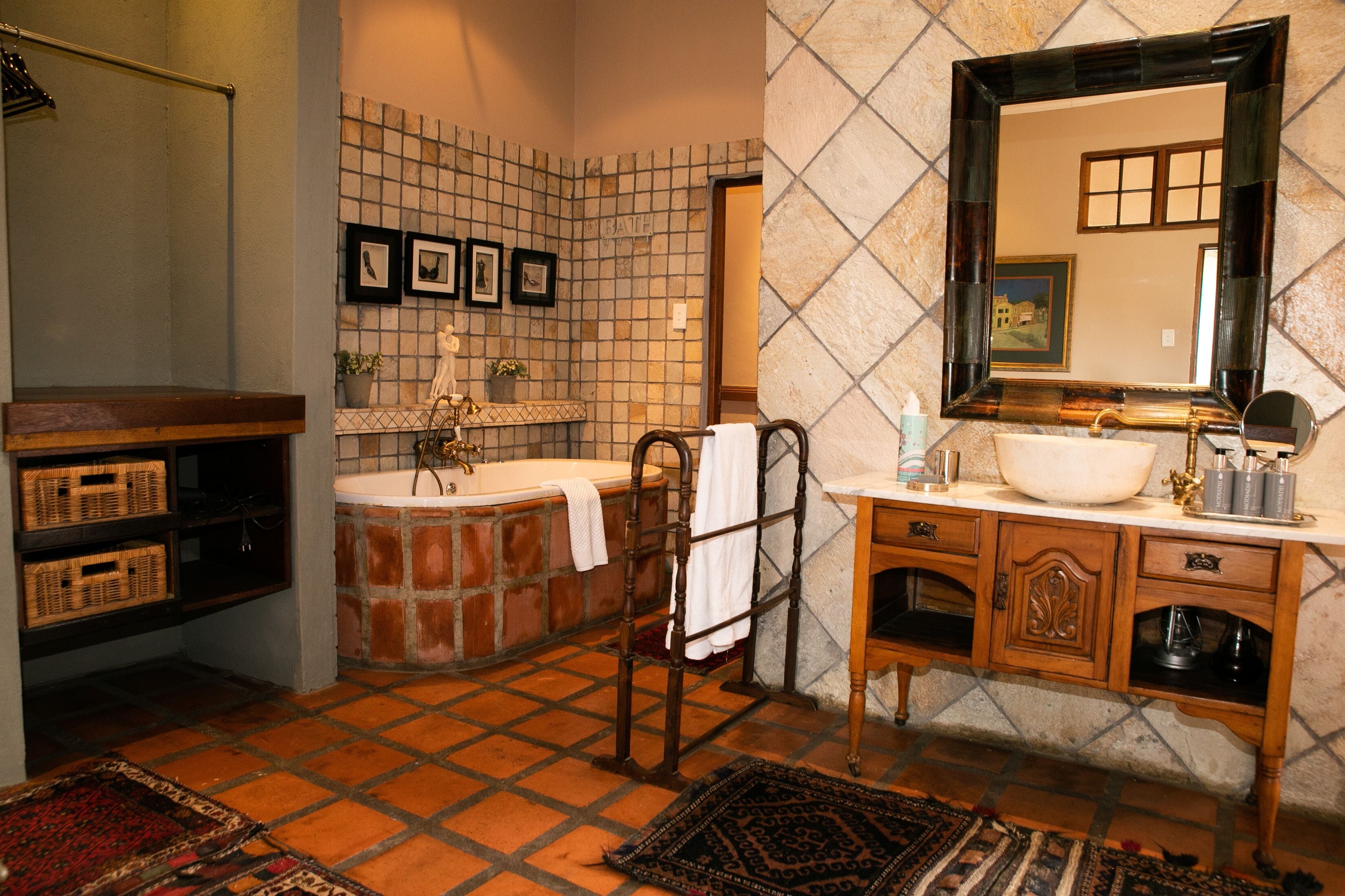 A bathroom with a bathtub, a wooden vanity, a large mirror, and a tiled floor.