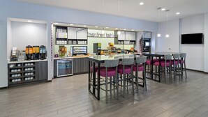 Una cocina moderna con barra, equipada con cafeteras y un refrigerador.