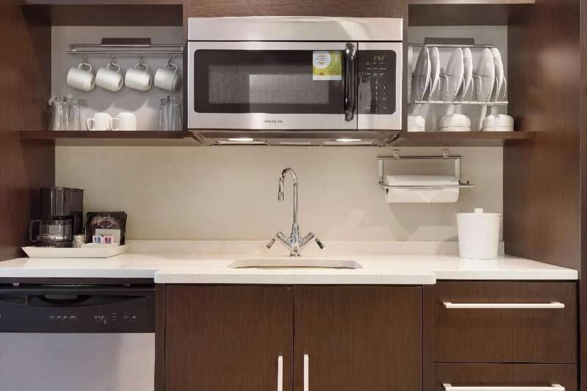 A modern kitchen with a built-in microwave, stainless steel appliances, and a coffee maker.