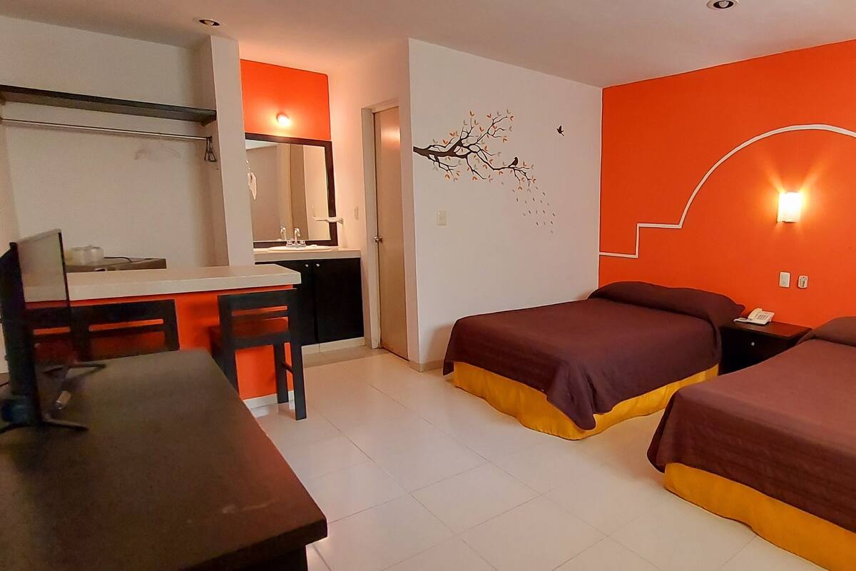 A hotel room with two beds, a desk, and a chair.