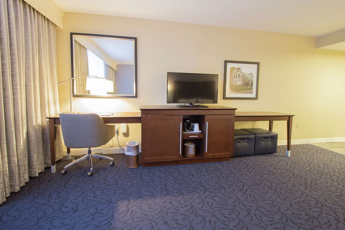 Une chambre d’hôtel équipée d’un bureau, d’une chaise, d’une télévision et d’une armoire avec des tiroirs.