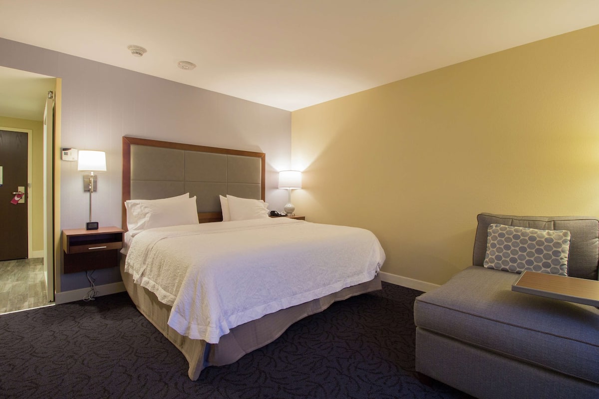 Une chambre d’hôtel comprenant un lit, des tables de chevet, une commode, un canapé et une lampe.