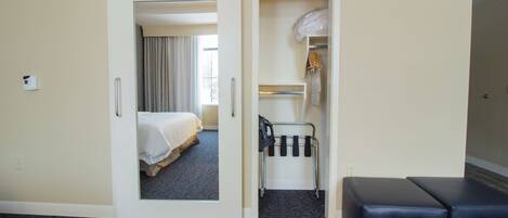 A hotel room with a bed, a coat rack, and a shoe rack.
