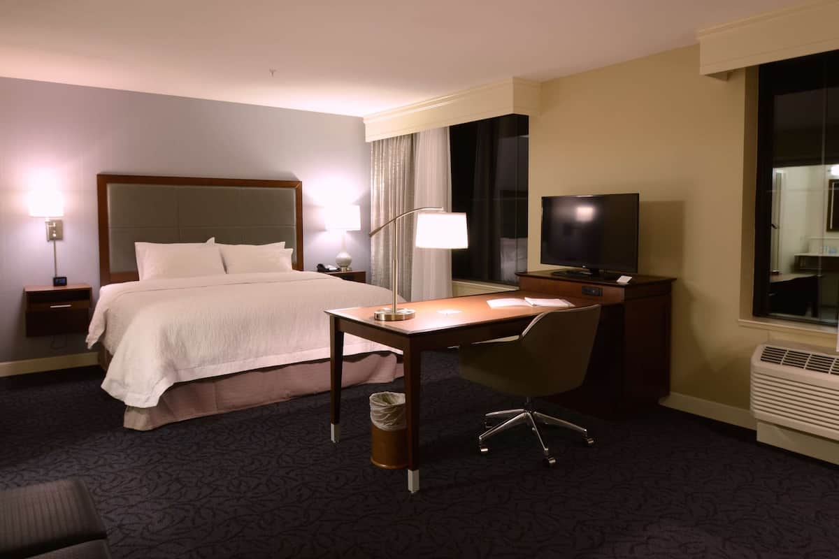 Une chambre d’hôtel équipée d’un lit, d’un bureau, d’une chaise, d’une télévision, d’une lampe et d’un appareil de climatisation.