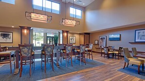 A spacious dining area with wooden chairs and tables, large windows, and decorative lighting fixtures.