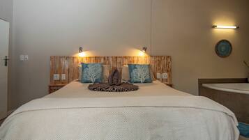 A hotel room with a large bed, wooden headboard, two wall-mounted lights, and a decorative wall piece.
