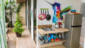 Una cocina compacta con lavamanos, encimera y refrigerador. Se observan plantas y utensilios de cocina.