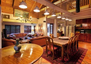 A dining area with a round wooden table, chairs, a vase, and a red patterned rug. - Waterkloof Apartments (Pretoria)