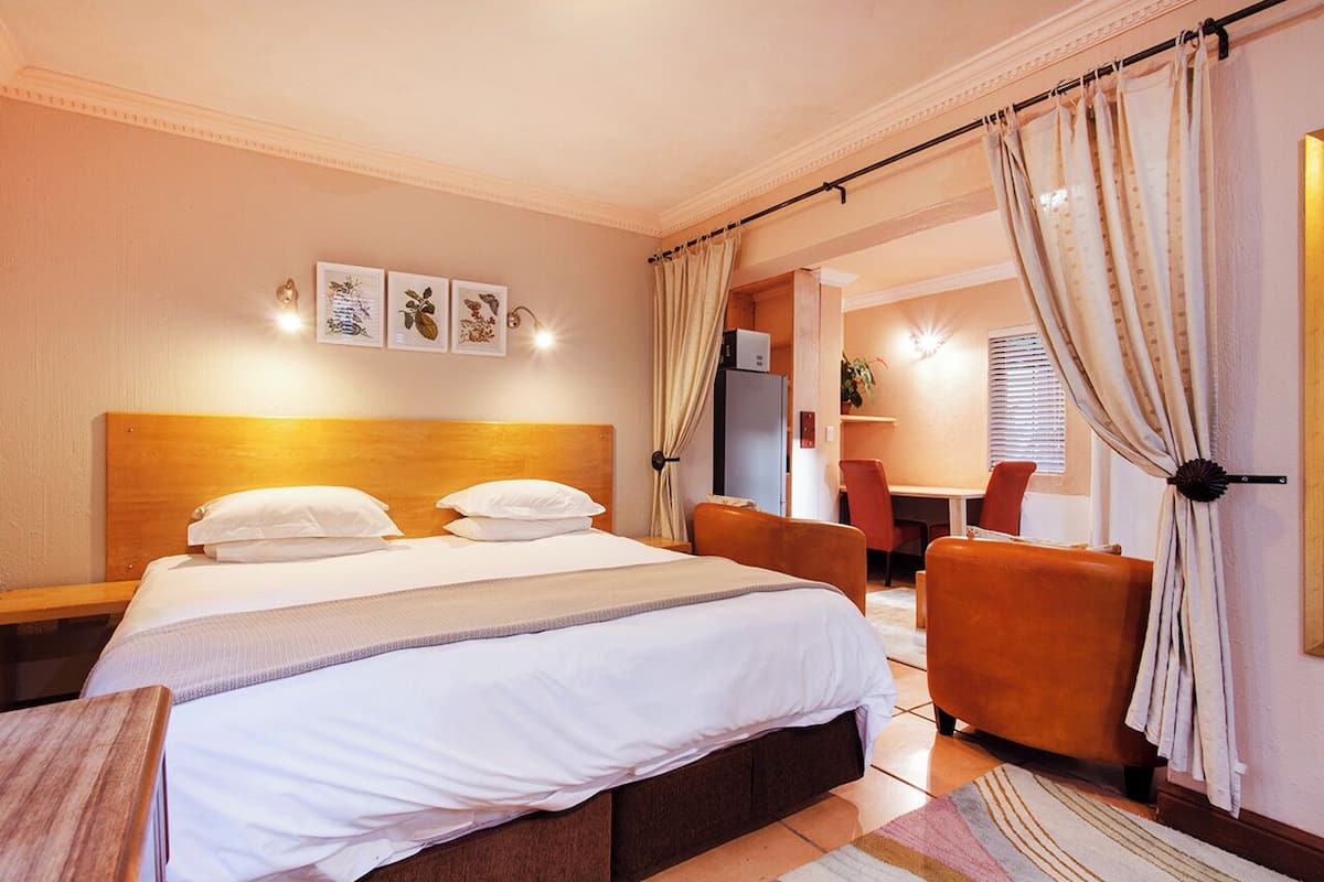 Una habitación de hotel con cama, una silla, escritorio y refrigerador.