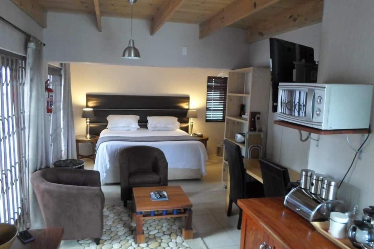 Un dormitorio con cama, mesita de noche, silla y escritorio con asiento.