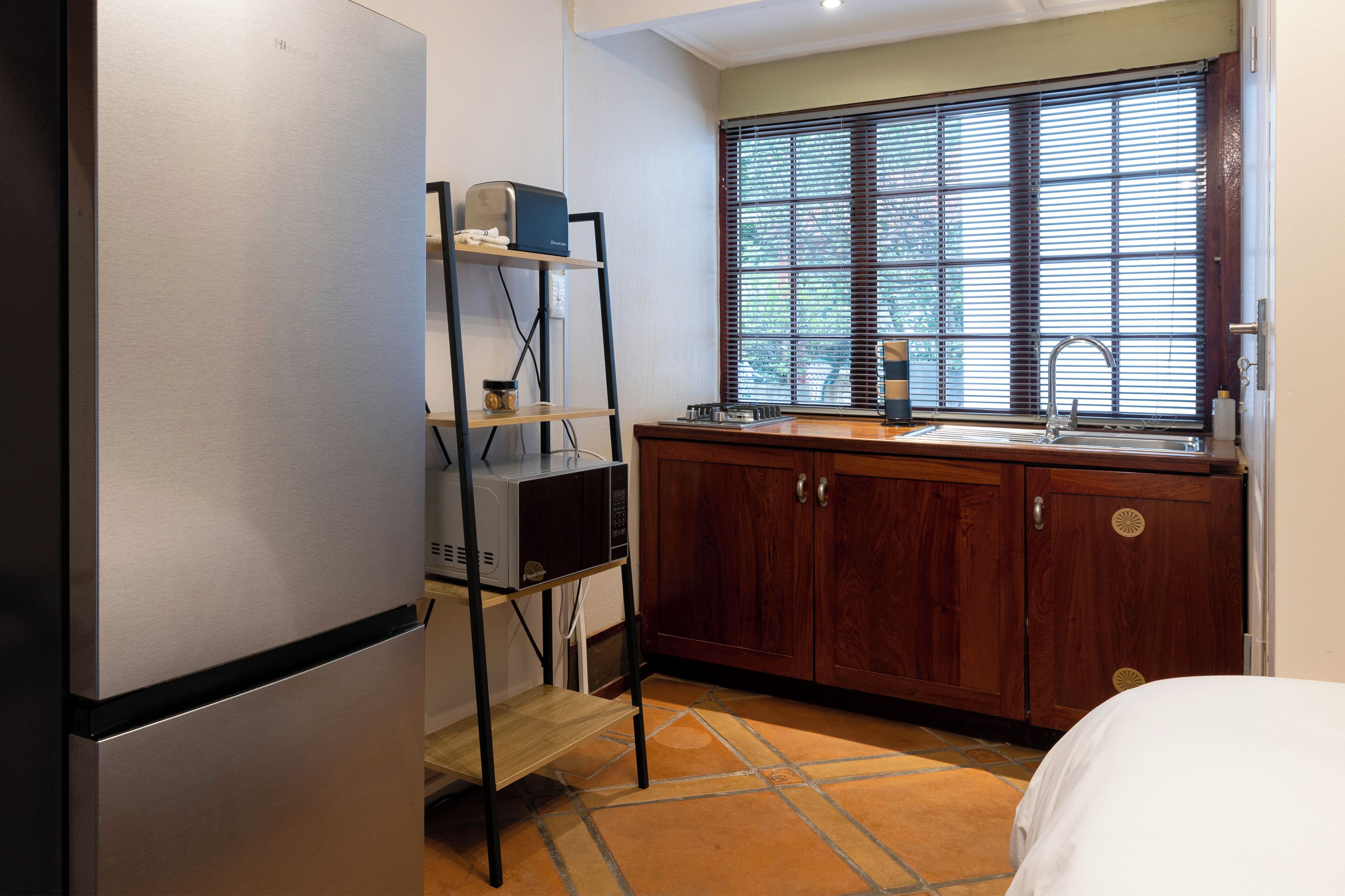 Una cocina equipada con refrigerador, microondas, lavamanos y gabinetes de madera.