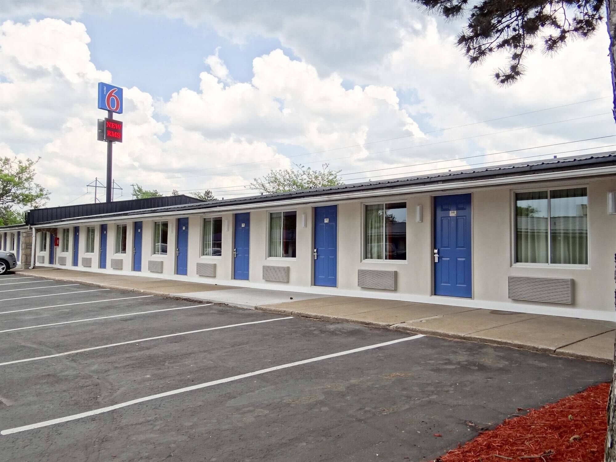 Um motel com uma fileira de quartos individuais, cada um com uma porta azul e uma janela.