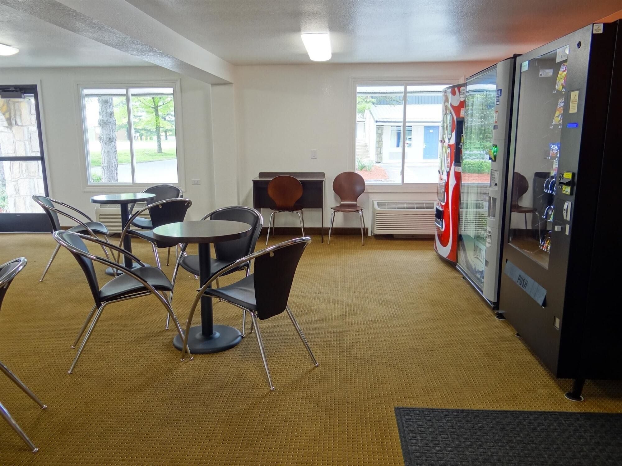 A conference room with a large table, chairs, a vending machine, and a view of the outdoors.