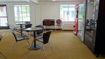 A conference room with a large table, chairs, a vending machine, and a view of the outdoors.