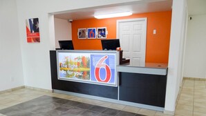 A reception desk with a digital display advertising a motel. - Motel 6 Erie, PA (Erie)
