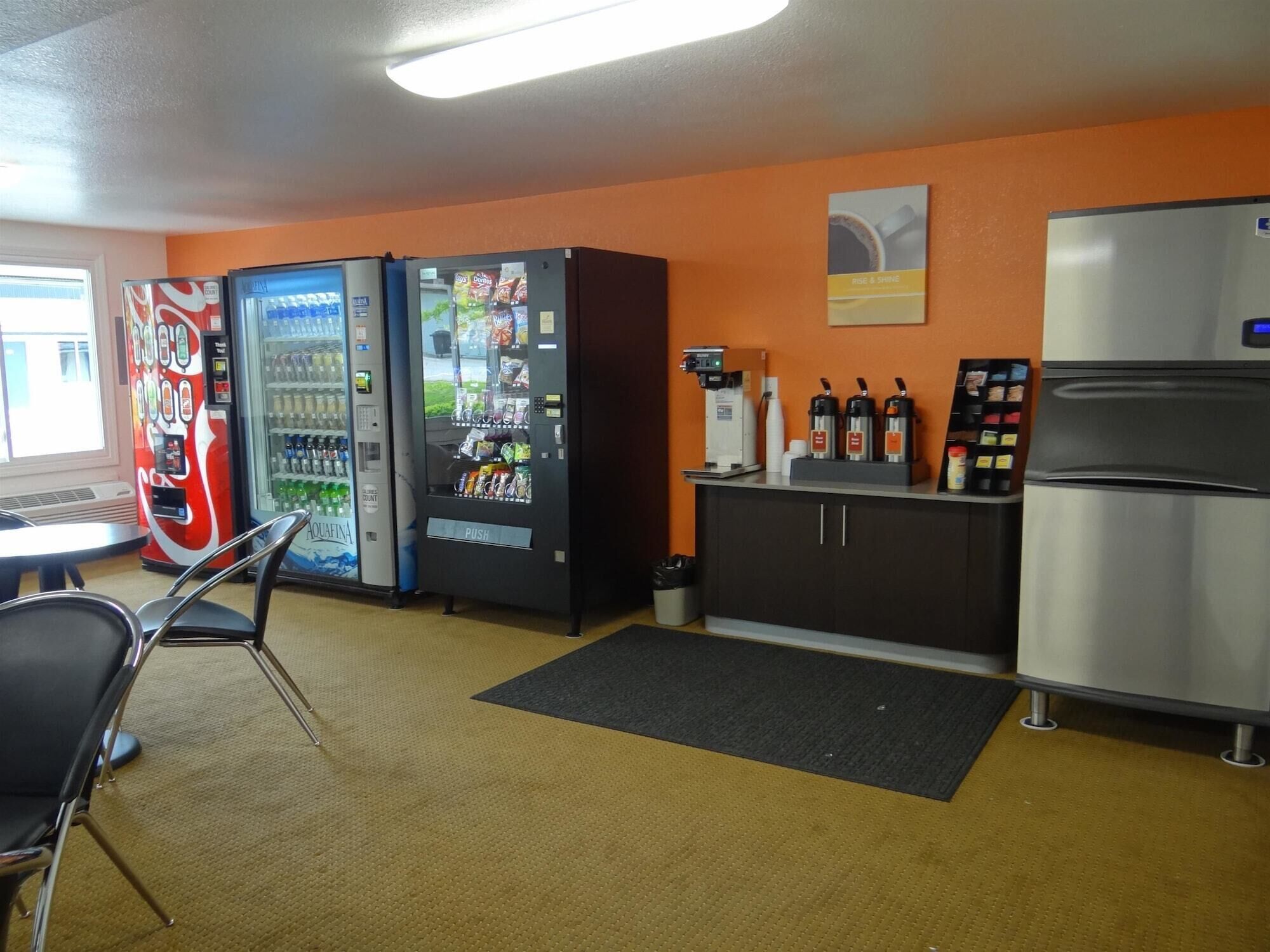A kitchenette with a refrigerator, coffee machine, and vending machines.
