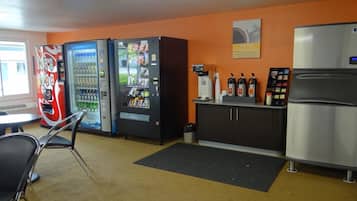 A kitchenette with a refrigerator, coffee machine, and vending machines.