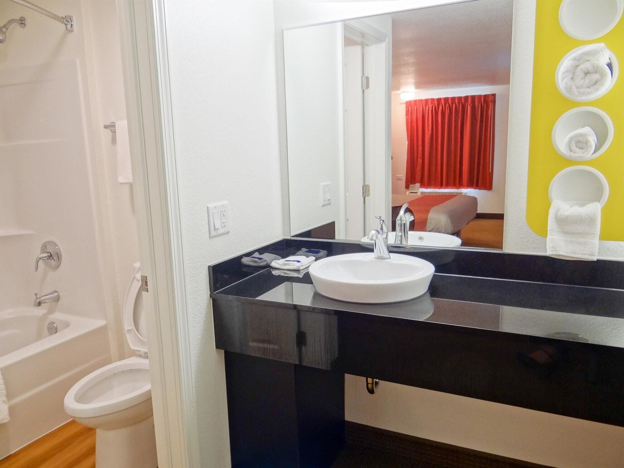 Une salle de bain moderne avec un plan de toilette noir, un lavabo blanc et un grand miroir.