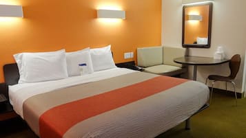 Een hotelkamer met een bed, een bureau, een stoel en een spiegel.
