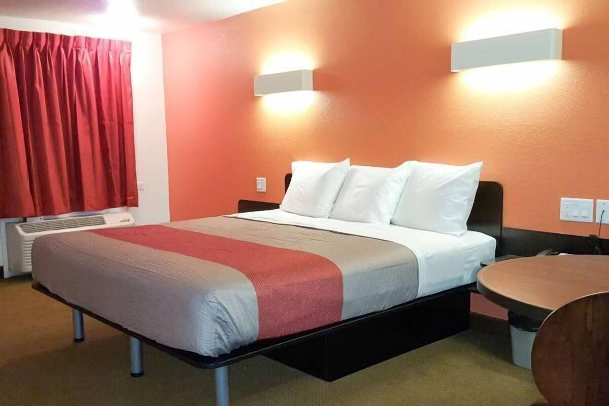 A hotel room with a bed, a desk, and a chair.