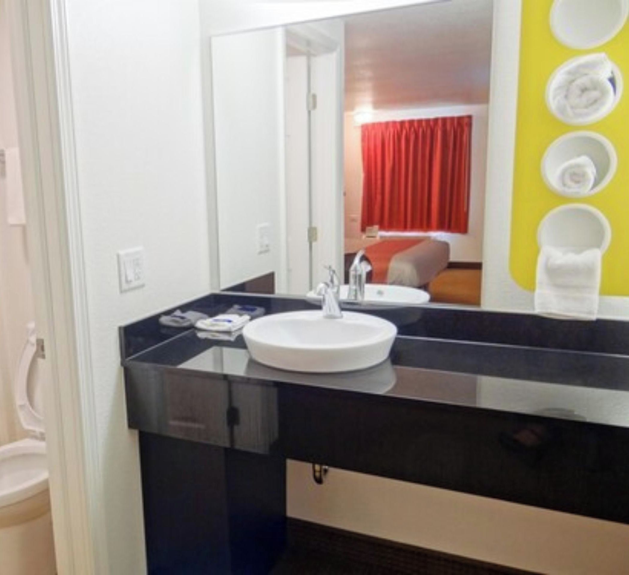 A modern bathroom with a black countertop, white sink, and a mirror.